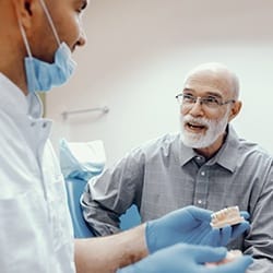 Older man speaking to dentist about implant dentures in Fairfax.