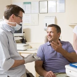 A dentist having a discussion with a male patient about Invisalign treatment