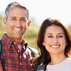 Smiling man and woman outdoors after gum recontouring