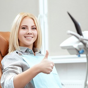 Woman smiling while giving thumbs up in dental chair
