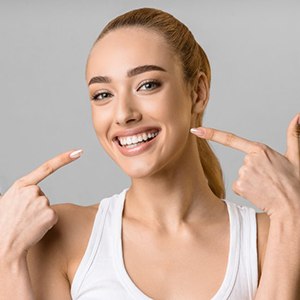 Woman smiling while pointing to her teeth