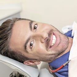 Man smiling in dental chair after dental crown restoration