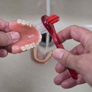 a person brushing their dentures