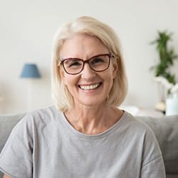 An older woman smiling on a couch.