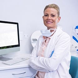 A denture dentist in Fairfax folding her arms and smiling.