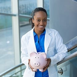 Denture dentist in Fairfax smiling while holding a piggy bank.