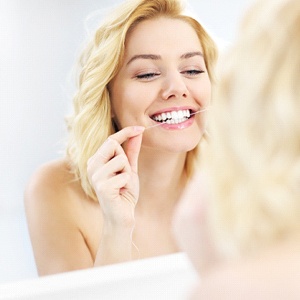 Woman flossing her teeth in Fairfax