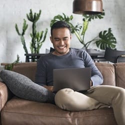 person with full dentures smiling while using laptop