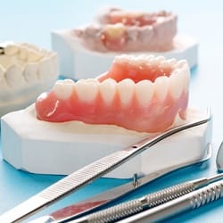 dentures sitting next to dental tools