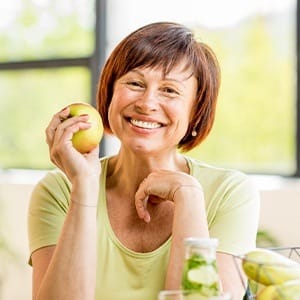 woman smiling and holding an apple
