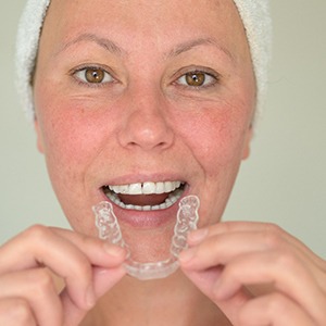 A middle-aged woman prepares to insert a mouthguard to protect her teeth before going to bed