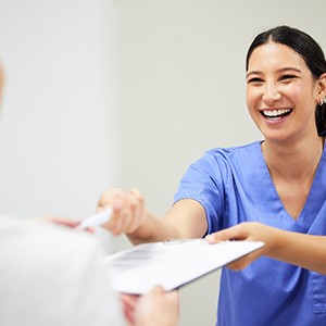 a person in scrubs handing a patient forms 