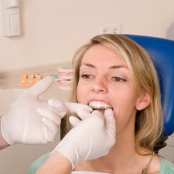 A dentist placing Invisalign aligners in a female patient’s mouth