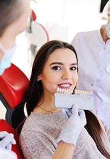 A dentist using a shade guide to determine the color of a patient’s veneers near the Mosaic District, VA