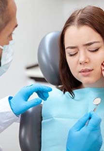 A young woman holding her cheek in pain because of a severe toothache near the Mosaic District, VA