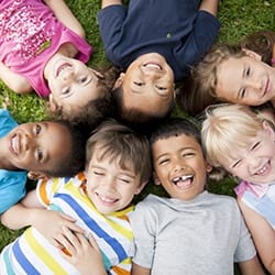 Smiling kids laying in grass after fluoride treatments