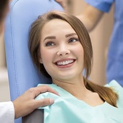Smiling woman in dental chair after tooth-colored filling treatment