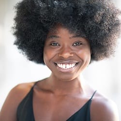 person smiling and standing outside after root canal therapy