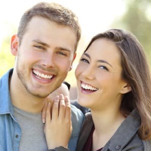 Man and woman smiling after receiving scaling and root planing