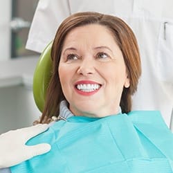 Smiling woman in dental chair during scaling and root planing treatment