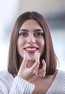 A young female holding an Invisalign aligner in preparation for putting it back into her mouth near the Mosaic District, VA