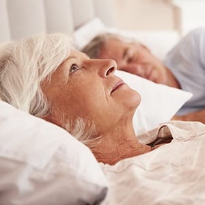 Woman in need of sleep apnea therapy awake in bed