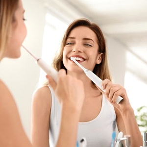 Woman brushing teeth after teeth whitening in Fairfax