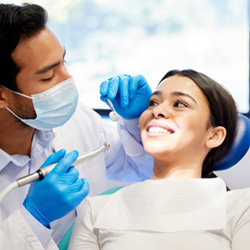 Woman smiling at dentist approaching her teeth