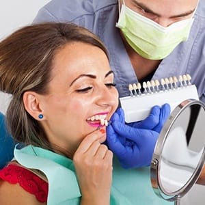 woman in red shirt trying on veneers in dental chair 