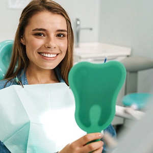 Female patient admiring smile after teeth whitening in Fairfax, VA