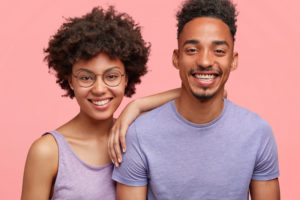 attractive couple smiling against pink background