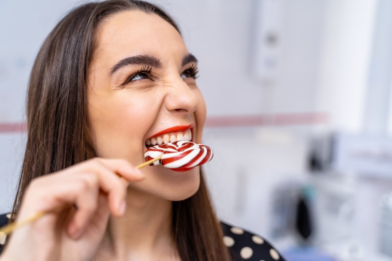 woman biting lollipop with healthy teeth.