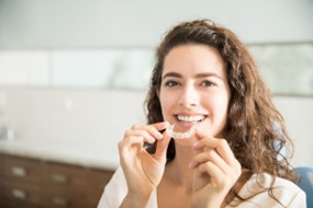 Woman holding Invisalign tray.