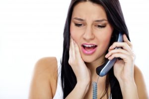 worried woman with toothache in Fairfax calling emergency dentist. 