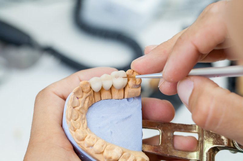 A dental technician working on a dental bridge