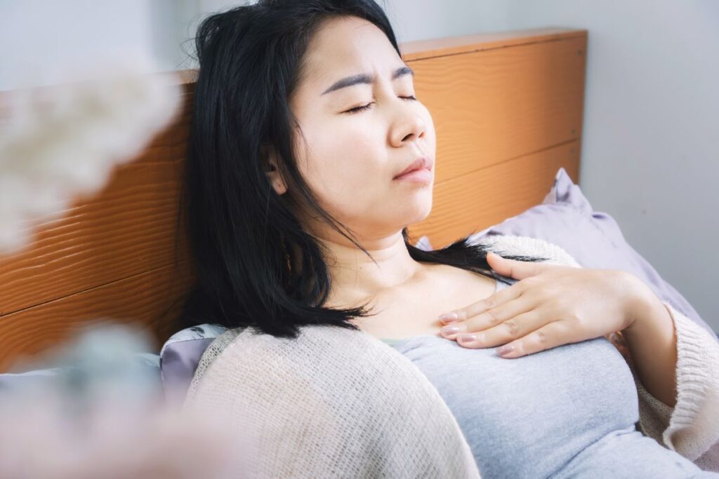 A woman with acid reflux symptoms lying in bed.