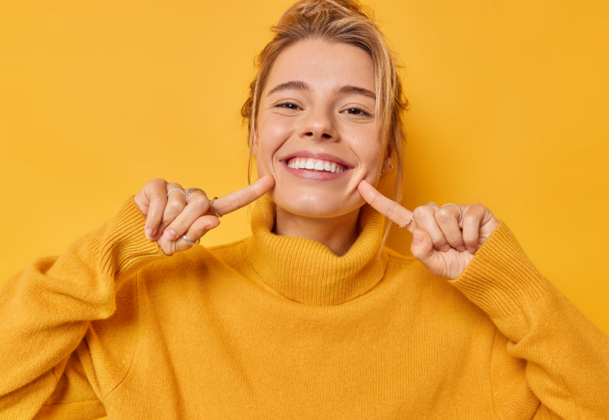 Woman in mustard yellow turtle neck pointing at smile